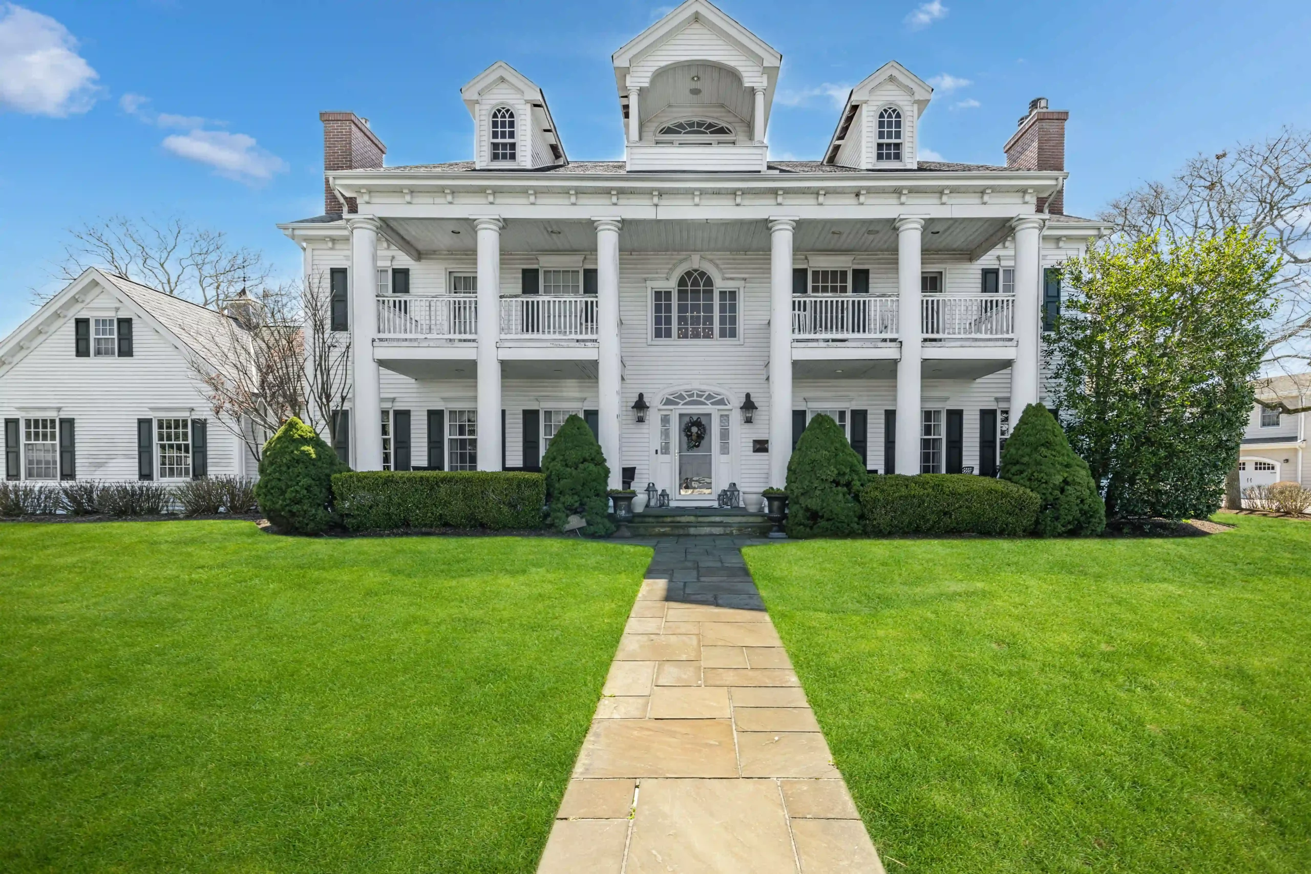 A spacious white house with a welcoming walkway to the entrance in spring lake, featured in real estate photography.